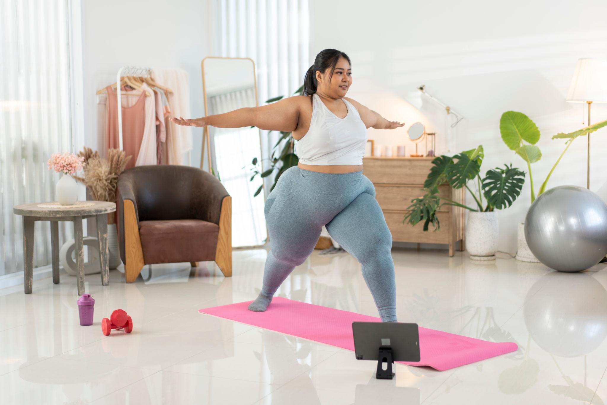 Человек с большим весом выполняет низкоударное кардио дома без прыжков